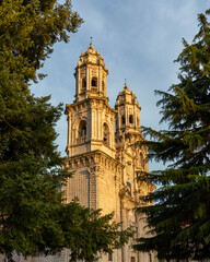 Bell Tower of Sobrado monastery in golden light framed between fir trees