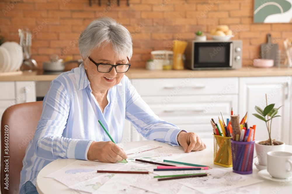 Sticker Senior woman coloring picture in kitchen