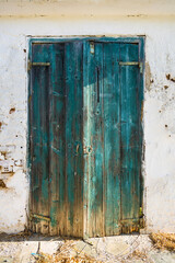 An old turquoise wooden door from a white shed with vintage charm.