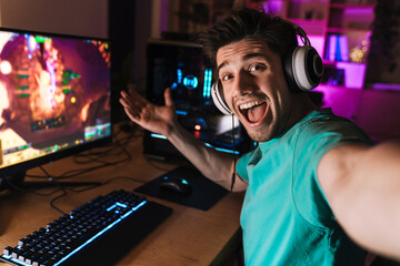 Image of excited man taking selfie photo while playing video game