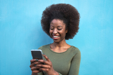 Young Afro woman using mobile smartphone - Happy African girl having fun with new trends technology apps - Youth millennial generation z and social influencer concept - Blue background