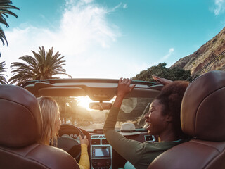 Young happy women doing a road trip in tropical city - Travel people having fun driving in trendy...