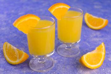 
Vodka with orange juice in small glasses on a blue background.