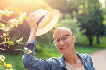 Happy young caucasian bald confident hipster woman take off hat and enjoying life after surviving...