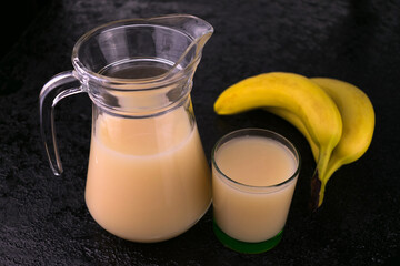 
Sweet banana juice in a jug on a black background.
Close-up.