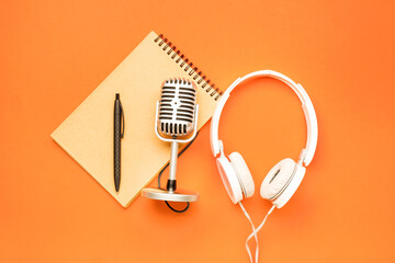 Headphones with microphone and notebook on color background