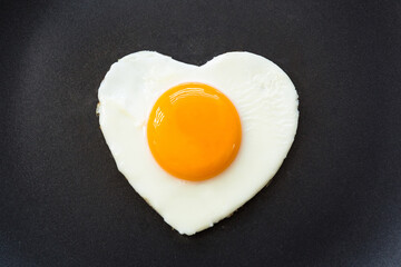 Fried egg in the shape of a heart in a pan