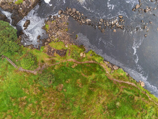 Small river flows by a green fields, West of Ireland, Aerial top down view.