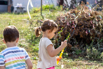 Children blowing bubbles.Outdoor image.Shot of adorable brother and sister blowing bubbles together outside.Cropped shot of two young siblings standing together and blowing bubbles during relaxing day