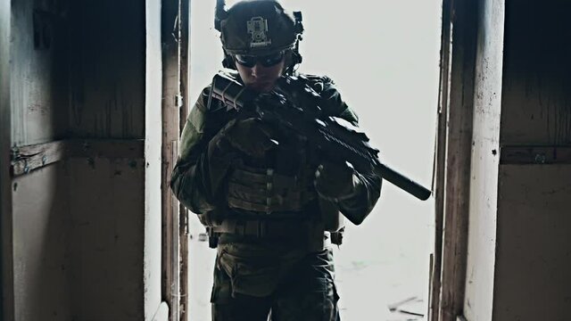Soldier in full US MARSOC armed with assault rifle run through the abandoned building. Military clash.