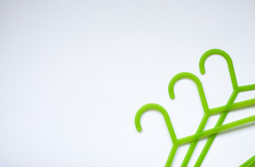 Three green plastic hangers for adults and children's clothing on white background with space for text. The concept of shopping, sales, nothing to wear, children's clothing