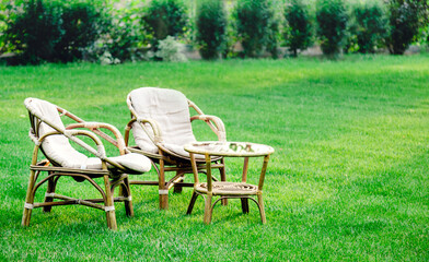 Two armchairs, wooden garden furniture on grass lawn outdoor for relaxing on hot summer days. Garden landscape with two chairs in nature. Rest in park cafe. Backyard exterior. Nobody