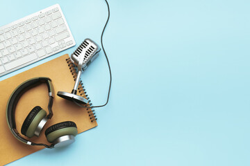 Headphones with microphone, computer keyboard and notebook on color background