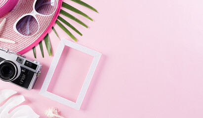 Beach accessories retro film camera, sunglasses, starfish, beach hat and sea shell on pink pastel background for summer holiday and vacation concept.