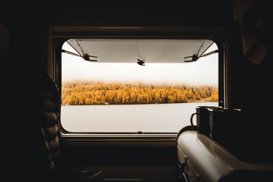 Bilck aus dem Fenster eine Campervans auf den Silvaplanersee bei St.-Moritz in den schweizer Alpen mit bew&ouml;lktem Himmel und Lerchen im Hintergund in herbstlichen Farben.