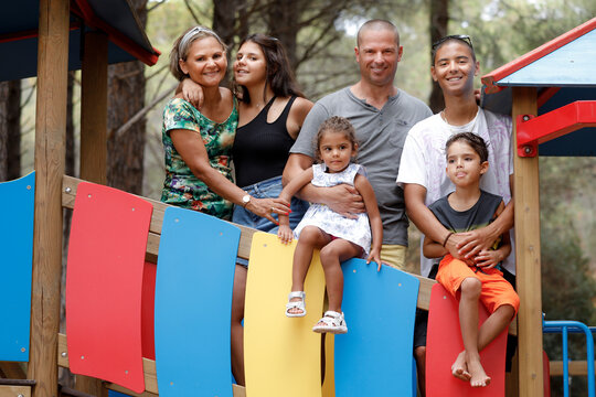 Bellissima famiglia Multientinica Italo - Brasiliana si raduna in un gruppo sopra una struttura colorata di giochi per bambini