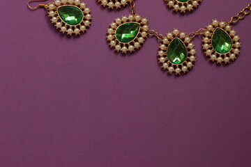 luxury green jewelry in the Baroque style on a purple background. Vintage, retro style.
copy space
