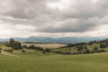 Fototapeta na wymiar Summer landscape panorama of meadow with hills and cloudy sky