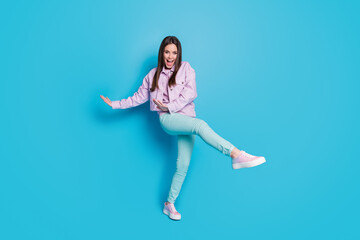 Fototapeta na wymiar Full length photo of attractive funny lady raise hands leg dancing students party good mood rejoicing wear casual denim violet jacket pullover pants shoes isolated blue color background