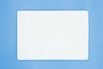 A rectangle empty white plate isolated on the light blue background.