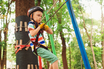 Extreme sport in adventure park. Little boy in the rope park pass obstacles.