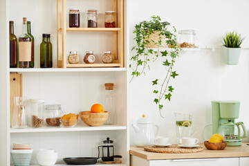Fototapeta na wymiar Background image of cozy kitchen interior with wooden shelves for spices and utencils decorated with plants, copy space
