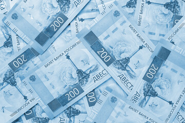 A field of Russian banknotes 200 rubles. Light blue tinted background or wallpaper on an economic or financial theme. Bills depict a monument to the scuttled ships in Sevastopol. Top view from above