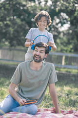 Smiling son putting earphones on his dads head, both feeling good