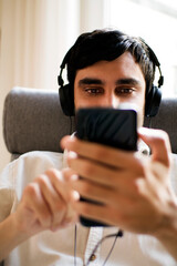 man sitting by the window listening to music with the mobile