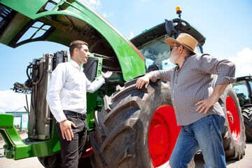 Professional farmer with a modern tractor, combine at a field in sunlight at work. Confident, bright summer colors. Agriculture, exhibition, machinery, plant production. Senior man on his machine with