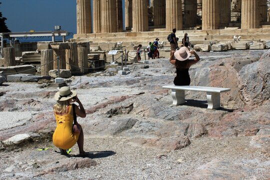 Greece, Athens, July 16 2020 - Tourists taking pictures at the archaeological site of Acropolis hill with Parthenon temple in the background.