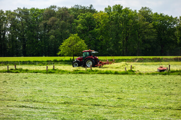 Rural landscape with tractor turning drying hay near Oldenzaal, Netherlands
