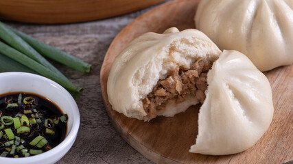 Delicious baozi, Chinese steamed meat bun is ready to eat on serving plate and steamer, close up,...