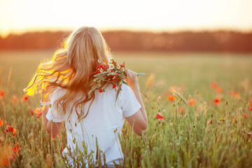 Pretty woman with long hair on poppy field at sunset. Back view. Fashion outdoor photo of beautiful  flying blonde  hair. Close up picture