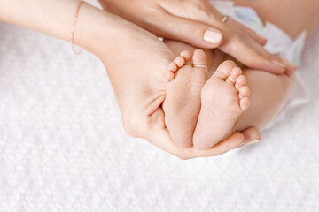 Obraz na płótnie Canvas Parent holding in the hands feet of newborn baby. Tiny newborn baby's feet on hands closeup. Mom and her child. Happy Family concept. Beautiful conceptual image of maternity. Copy space
