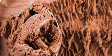 Full ice cream scoop in chocolate ice cream tub. Macro texture banner