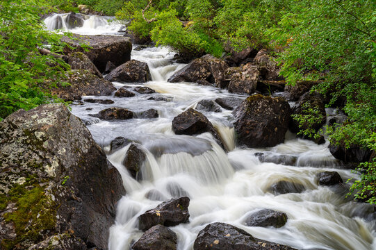 A beautiful scene of a small stream with white waters photographed in the Lapland wilderness.