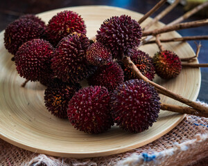 The exotic pulasan tropical fruit or scientific name Nephelium Mutabile on a wooden plate. Selective focus.