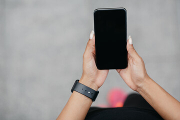 Smartphone for fitness blog. Girl with fitness tracker holds phone with blank screen