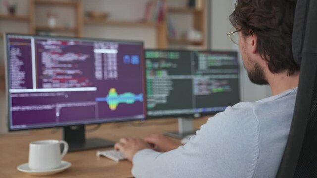 A handsome young businessman is working with his computer sitting in the office