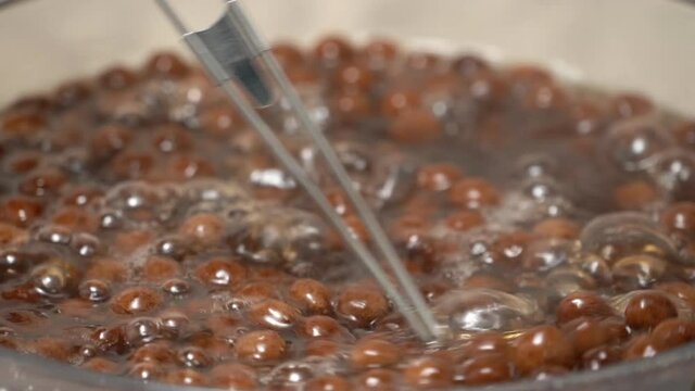 Cooking, boiling brown sugar flavor tapioca pearl balls, ingredient of bubble tea, preparing food and drink, close up, recipe cookbook steps design concept, slow motion.