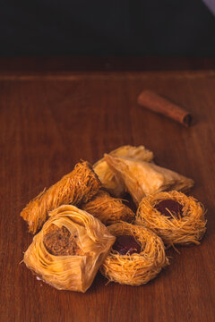 group of Syrian sweets (burma, baklawa, kneff, balewa, FAISALIE,) on a rustic wooden board and black background