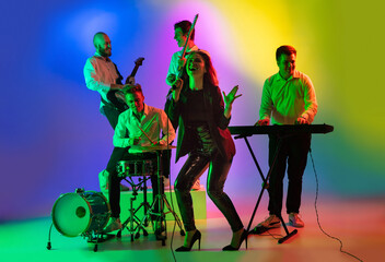Motion. Young caucasian inspired and expressive musicians, band performing on multicolored...