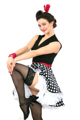 Naklejka premium A retro girl is pinuped in black stockings and a polka dot skirt. Beautiful brunette in the style of the fifties.