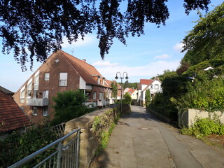 Wohngebiet in Hanglage mit schmaler Straße und Mauer bei Sonnenschein in Oerlinghausen am...