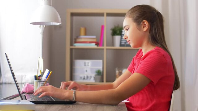 children, education and learning concept - teenage student girl with laptop computer writing to notebook at home