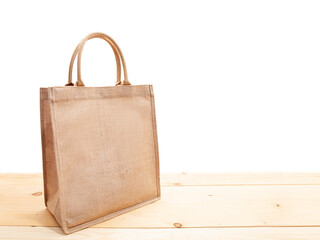 Eco friendly canvas shopping bag on the wooden table with white background (side viewed)