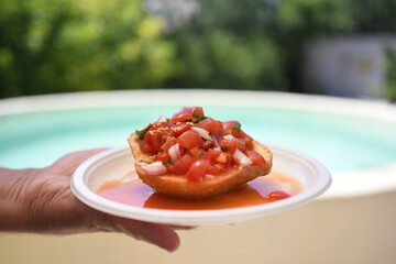 Delicious bruschetta with cherry tomatoes, basil and onion.
on background of a swimming pool