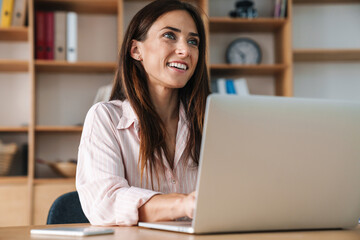 Image of happy businesswoman smiling while working with laptop