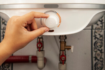 A woman's hand sets the temperature in the electric boiler